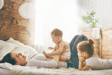 Mutter liegt gemeinsam mit 2 Kindern in Familienbett