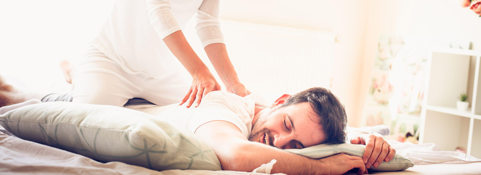 Frau gibt ihrem Partner auf gemeinsamen Bett eine Massage