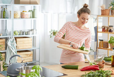 Junge Frau bereitet in Küche gesundes Essen aus Obst und Gemüse vor