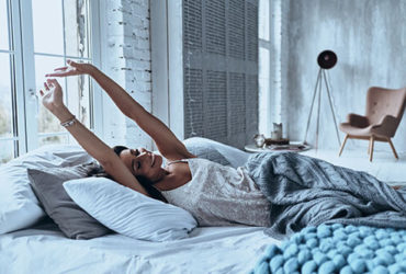 Frau wacht morgens ausgeschlafen und entspannt auf