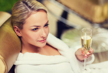 Schöne Frau entspannt nach Sauna mit Champagner in Hand