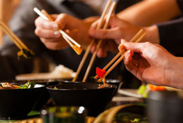 Leute essen Gerichte aus Asiatisches Küche mit Stäbchen
