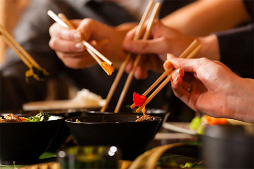 Leute essen Gerichte aus Asiatisches Küche mit Stäbchen
