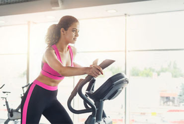 Frau trainiert auf Crosstrainer zuhause