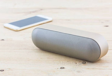 Helle Bluetooth Lautsprecher mit weißem Smartphone