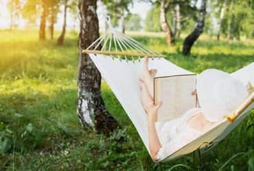 Frau liest Buch in Outdoor Hängematte
