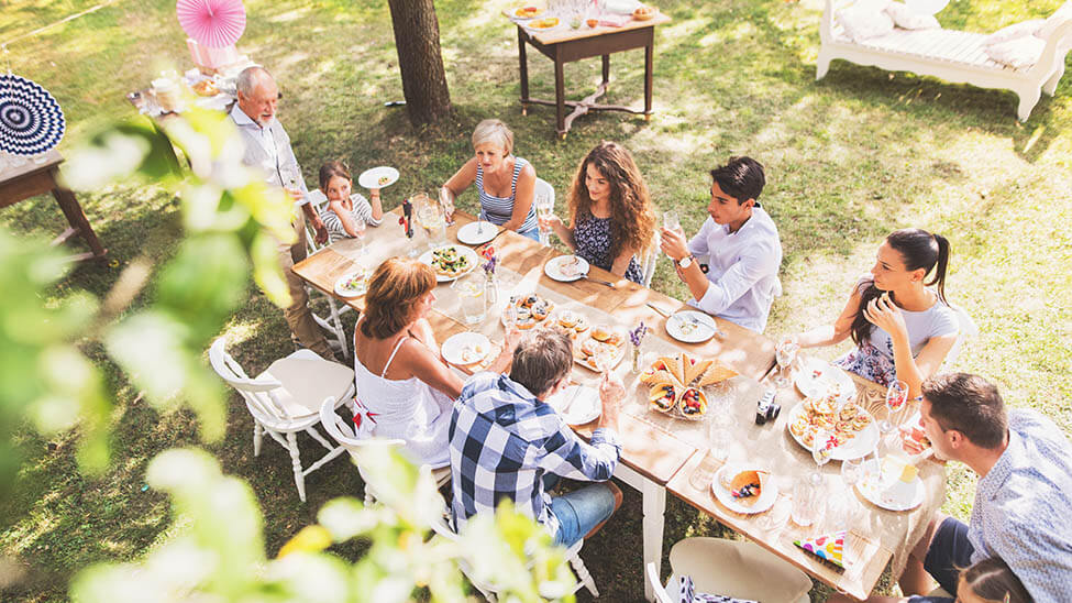 Große Familie feiert Gartenparty mit gedecktem Tisch auf Rasen