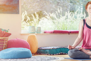 Frau meditiert mit Meditationskissen