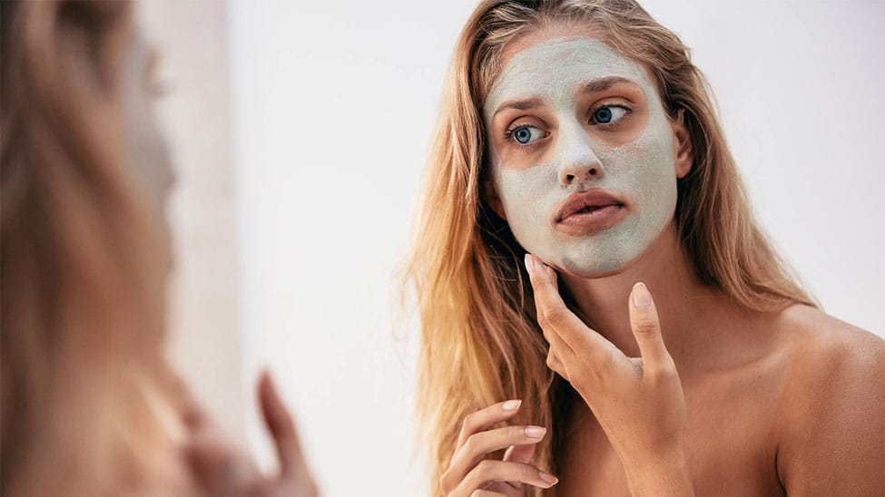 Frau mit Gesichtsmaske aus Creme