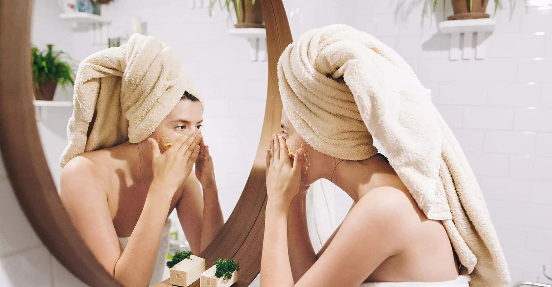 Frau mit Gesichtsmaske vor dem Spiegel im Bad