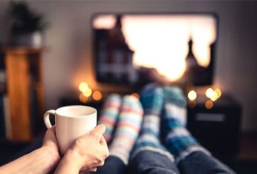 Paar bei Filmabend mit Wollsocken und Tasse Tee vor Fernseher