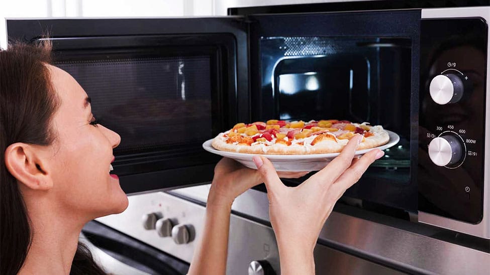 Frau legt Pizza in Pizzaofen für Zuhause