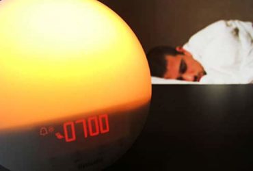 Mann schläft neben Lichtwecker