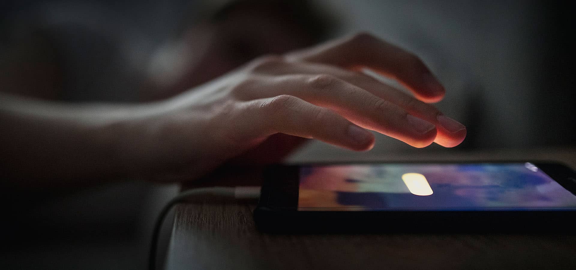 Wecker App auf Smartphone nachts neben Bett