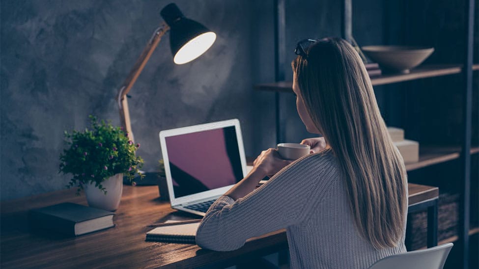 Frau arbeitet mit Schreibtischlampe an Bürotisch