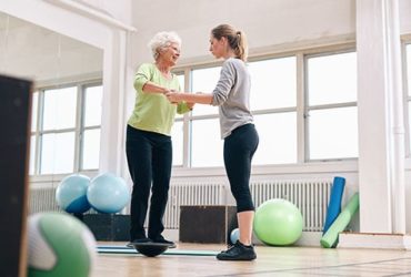 Alte Frau trainiert mit Balanceboard