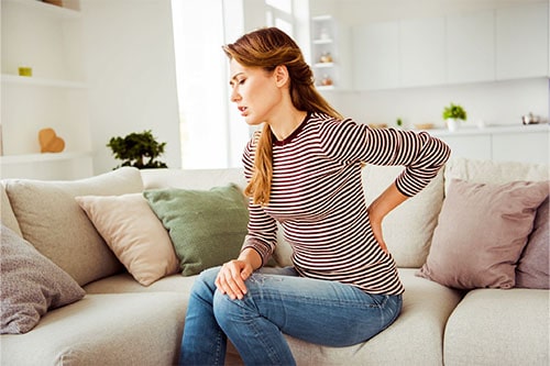 Frau mit Rückenschmerzen braucht Massagekissen