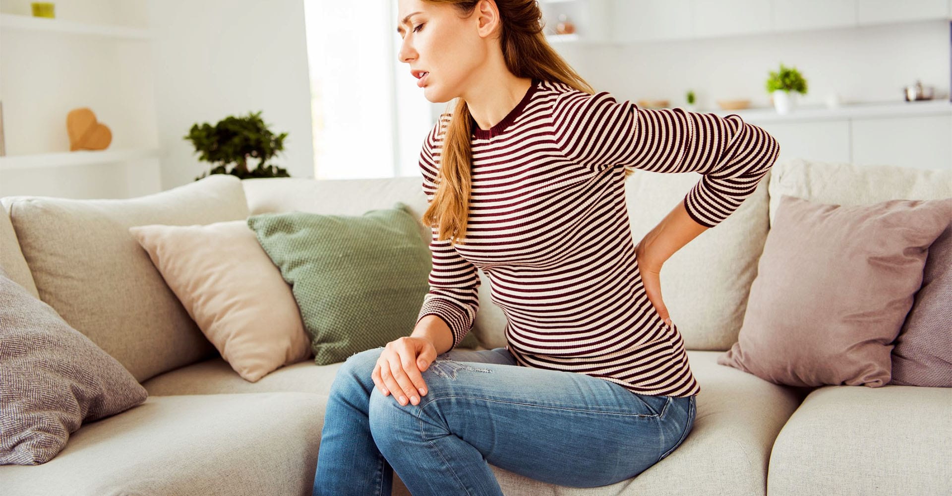 Frau mit Rückenschmerzen braucht Massagekissen