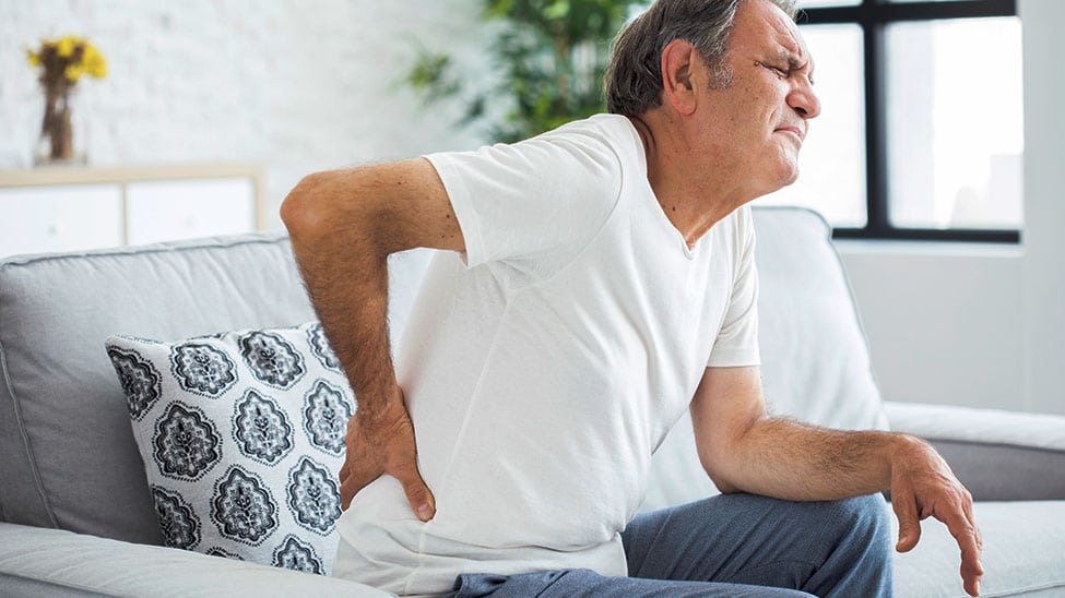 Mann mit Rückenschmerzen braucht Massagekissen