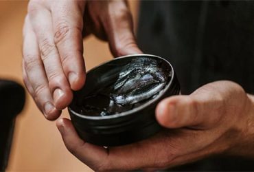 Mann mit schwarzem Haarwachs in Händen
