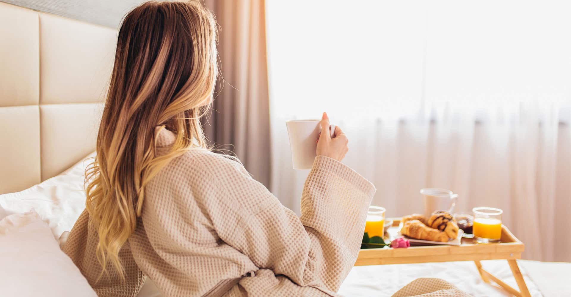 Frau in Bademantel und Frühstück im Bett