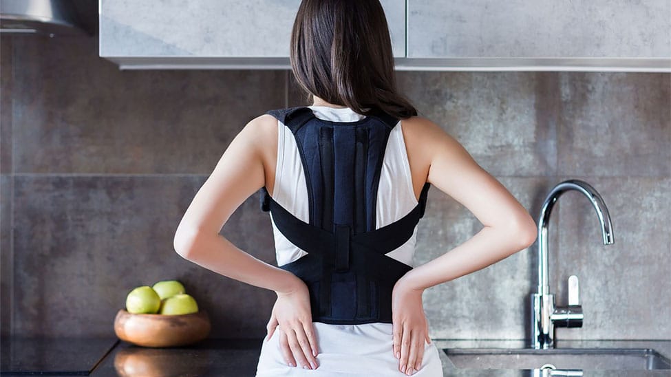 Frau mit Rückenbandage in Küche