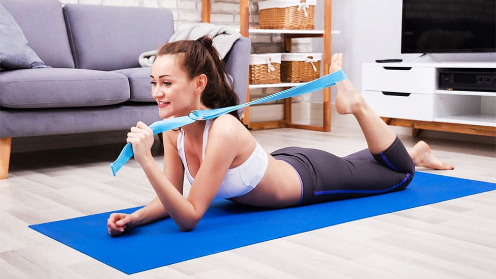 Frau trainiert zuhause mit Yogagurt