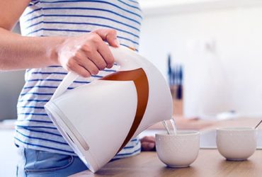 Frau macht mit Wasserkocher Tee