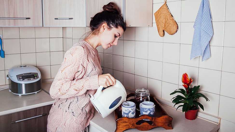 Frau mit Wasserkocher in Küche