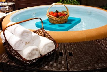 Korb mit Tüchern auf Whirlpool-Umrandung aus Rattan