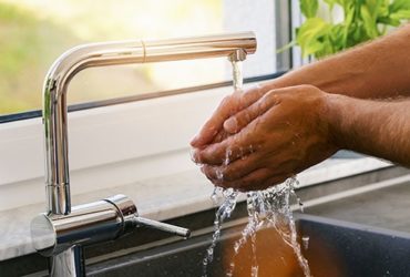 Mann wäscht sich Hände zur Hygiene über Spülbecken