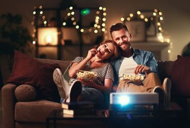 Paar schaut im Wohnzimmer Film mit Mini Beamer