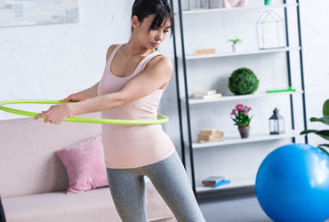 Frau trainiert zuhause mit Hula Hoop Reifen