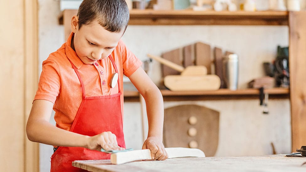 Junge schleift an Werkbank für Kinder