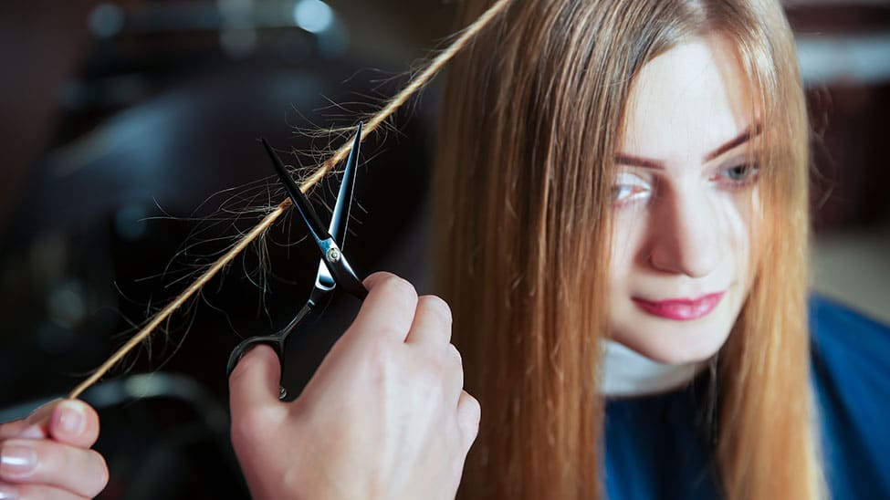 Jungem Maedchen werden mit Friseurschere Haare geschnitten