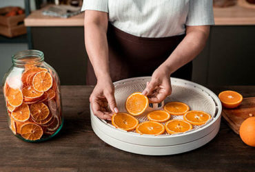 Mann legt Orangen in Dörrautomat