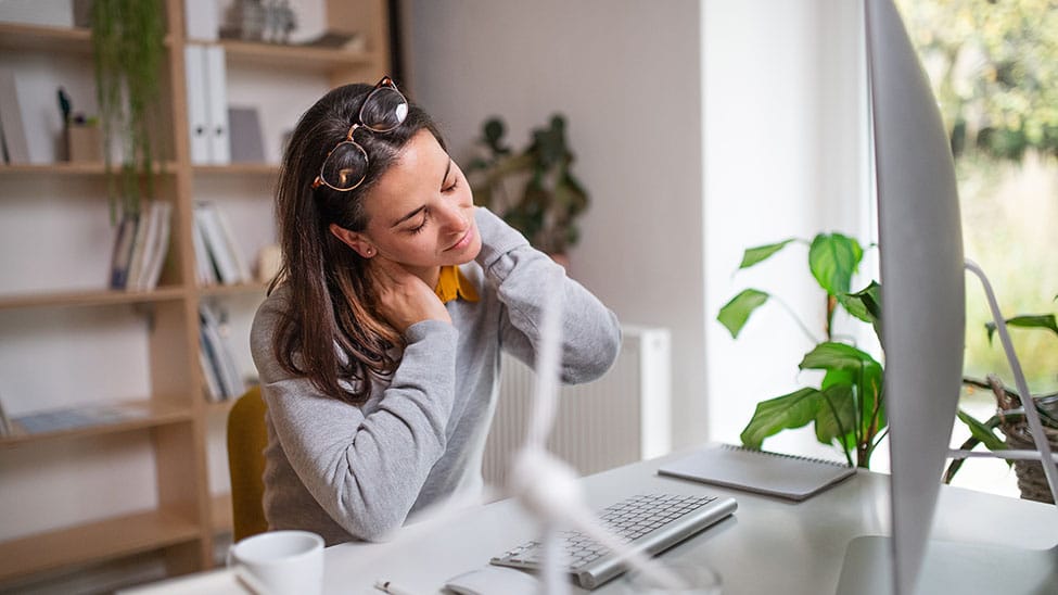 Frau hat Nackenschmerzen im Home Office