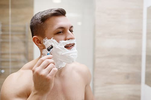 Mann rasiert sich mit Nassrasierer und Rasierschaum