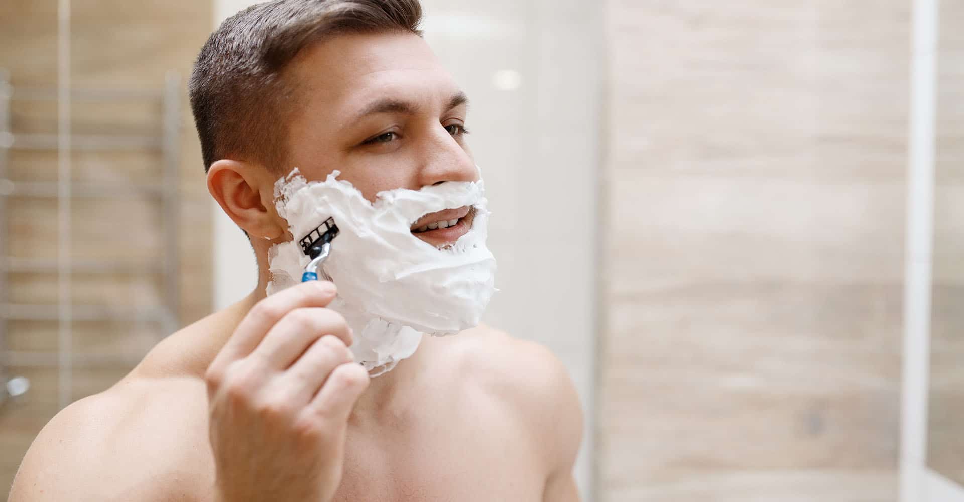 Mann rasiert sich mit Nassrasierer und Rasierschaum