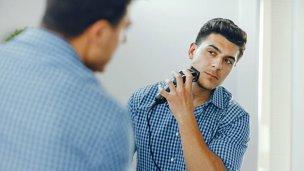 Mann rasiert sich mit elektrischem Rasierapparat