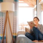 Frau genießt Leben und entspannt bei einem Buch auf Sofa zuhause