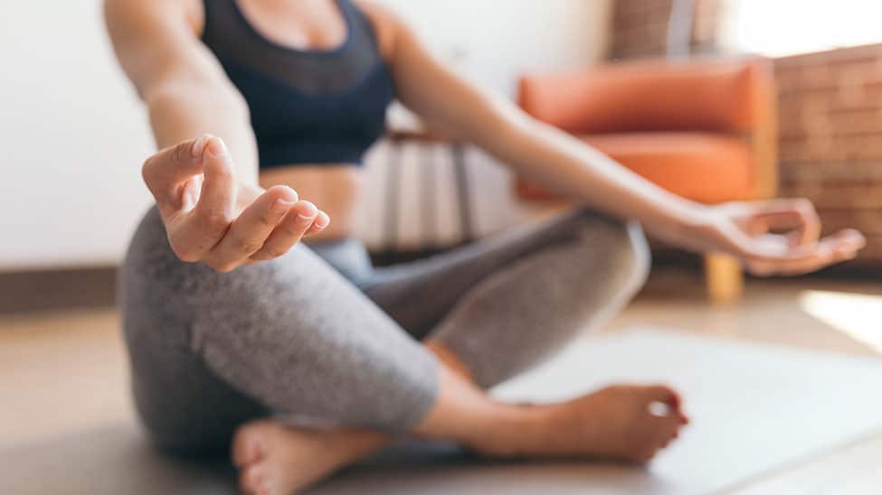 Frau meditiert auf Yogamatte im Schneidersitz