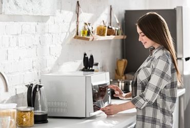 Mädchen nutzt Mikrowelle in Küche