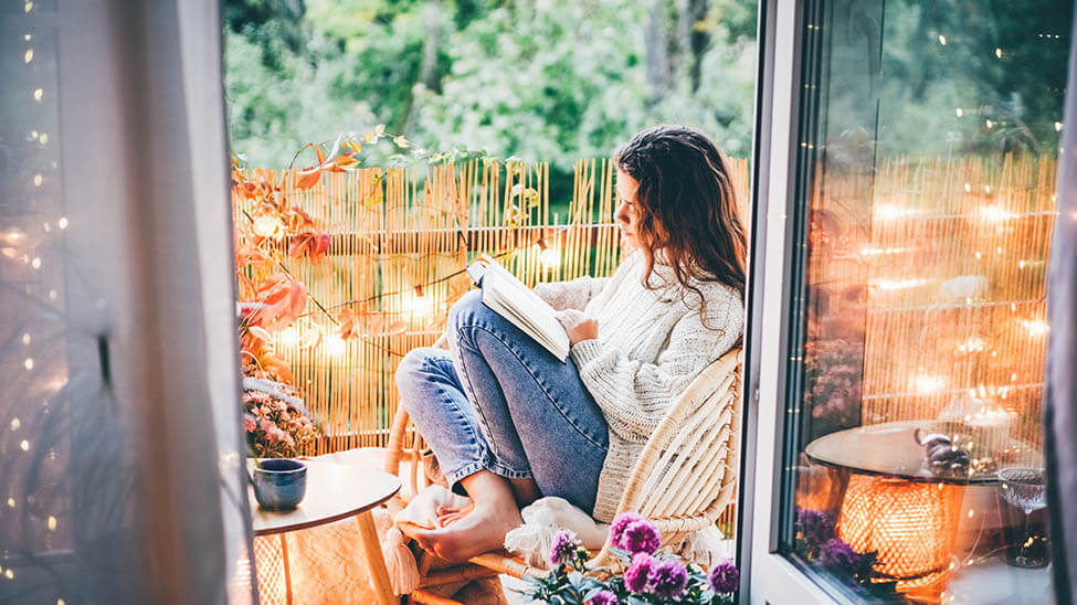 Frau liest gemütlich auf Balkon