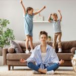 Mutter führt neben ihren Kindern Entspannungstübung in Form von Meditation durch
