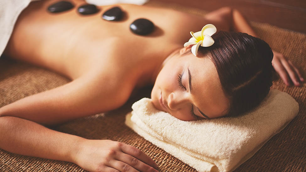 Frau genießt Hot Stone Massage auf elektrischer Massageliege