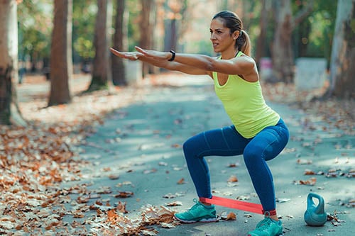 Frau trainiert mit Fitnessband um Beine in Park