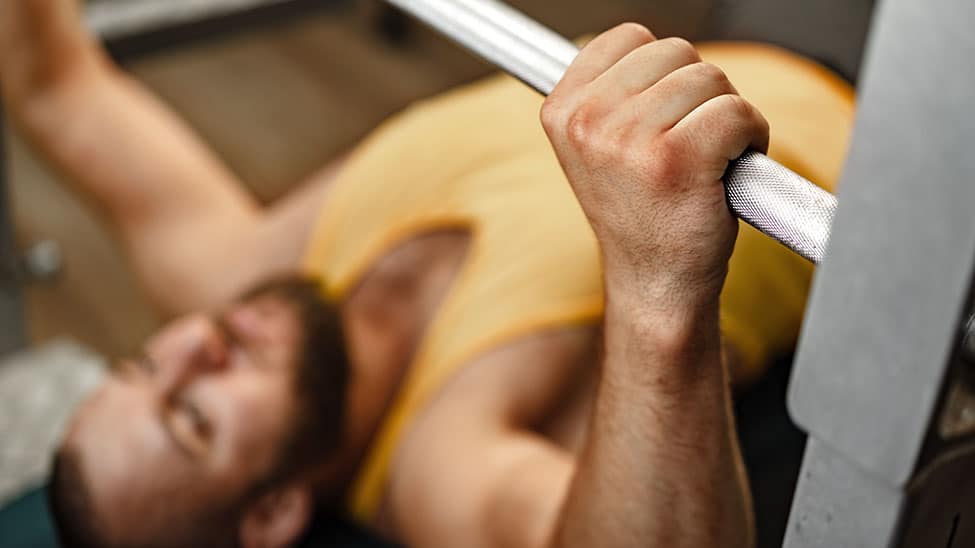 Muskulöser Mann macht Bankdrücken mit Fitnessturm